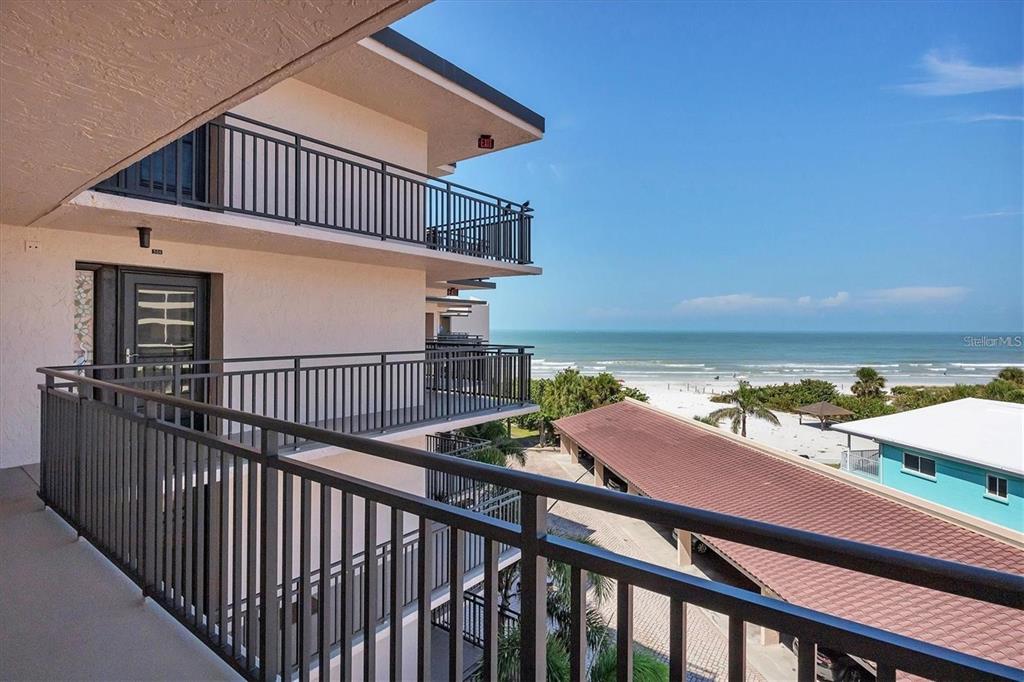 A view from a balcony overlooking a beach, parking area, and multi-story apartment building — 6480 MIDNIGHT PASS ROAD UNIT 506, SARASOTA, FL