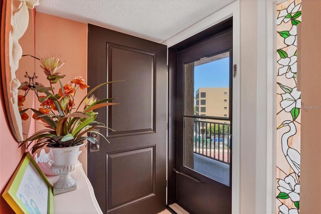 An interior entryway features a dark brown door, a potted plant, and a stained-glass window — 6480 MIDNIGHT PASS ROAD UNIT 506, SARASOTA, FL