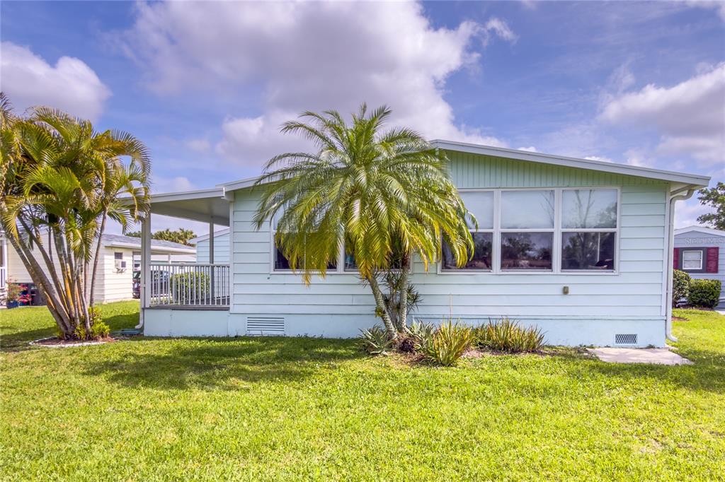 A light green manufactured home features a palm tree in the front yard — 117 HERON COURT, ELLENTON, FL
