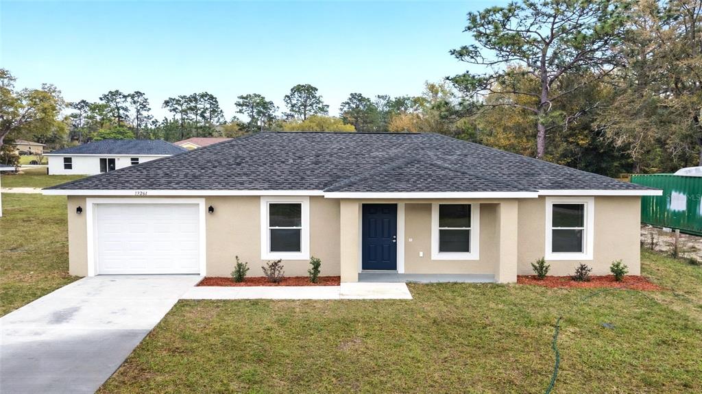 A single-story house with a beige stucco exterior, a one-car garage, and a covered porch — 1802 SW HILLIARD AVENUE, DUNNELLON, FL