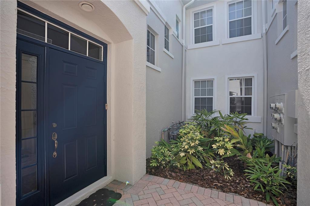 A dark blue front door opens onto a brick-paved entryway with a small garden bed — 926 RIVER BASIN COURT UNIT 201C, BRADENTON, FL