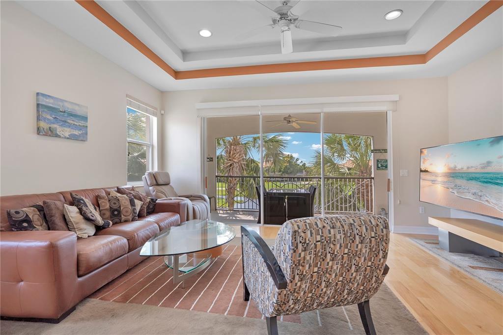 A living room features a leather sofa, patterned armchair, glass coffee table, and sliding glass doors — 926 RIVER BASIN COURT UNIT 201C, BRADENTON, FL
