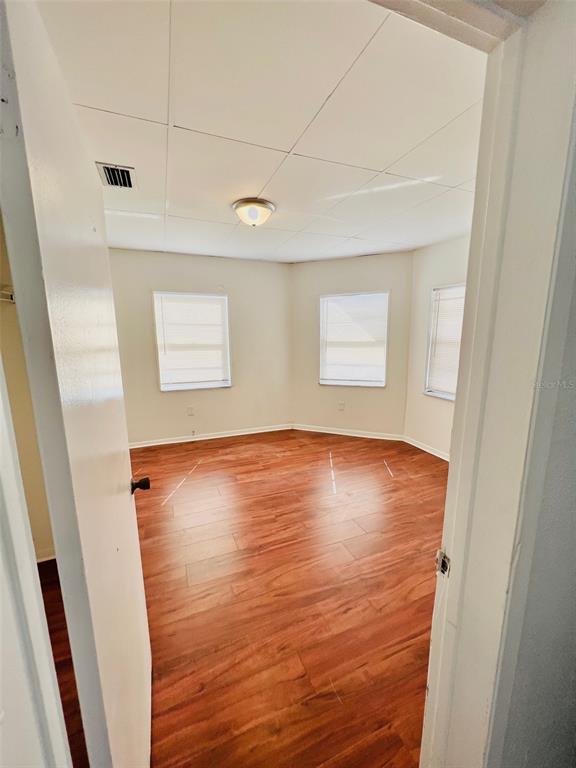 An empty room features wood-look flooring, white walls, and a drop ceiling with a light — 2507 ARMENIA, TAMPA, FL