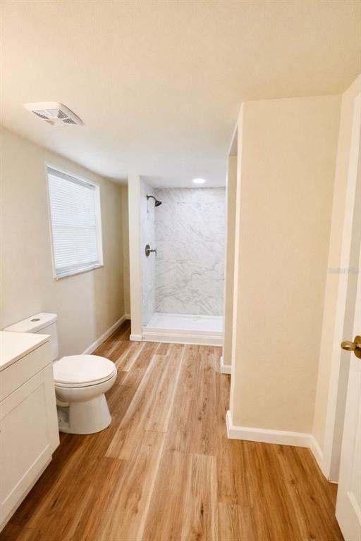 A bathroom features light wood-look flooring, a white vanity, a toilet, and a tiled shower — 2507 ARMENIA, TAMPA, FL
