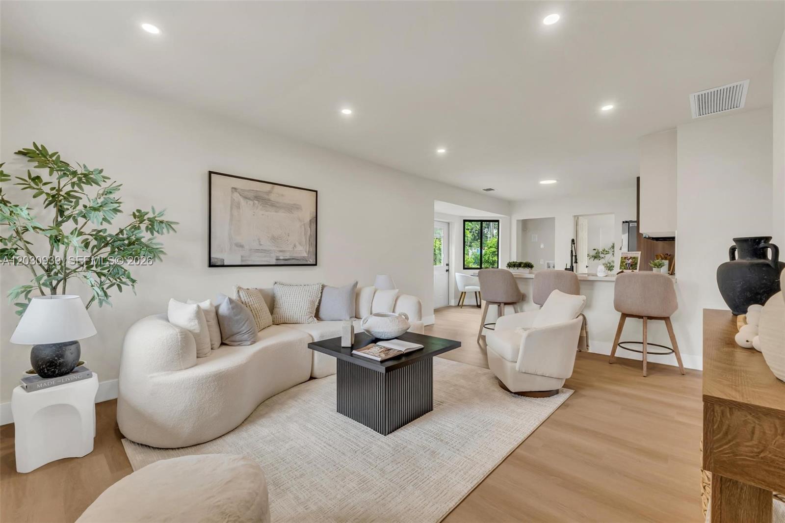 A bright living room features a curved sofa, a black coffee table, and an open kitchen — 2651 Fletcher Ct, Hollywood FL 33020, HOLLYWOOD, FL