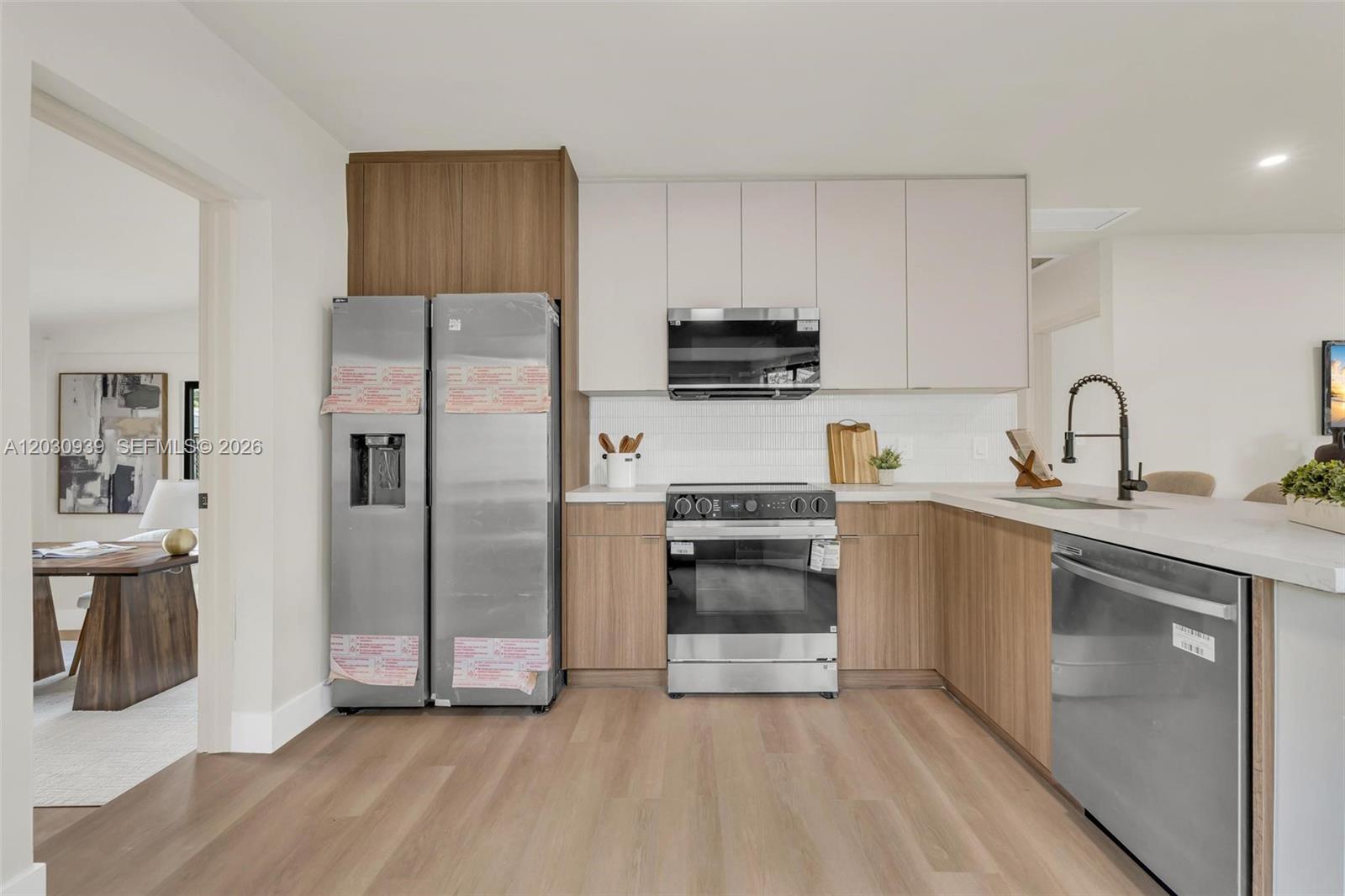 A modern kitchen features stainless steel appliances, wood-grain lower cabinets, and white upper cabinets — 2651 Fletcher Ct, Hollywood FL 33020, HOLLYWOOD, FL
