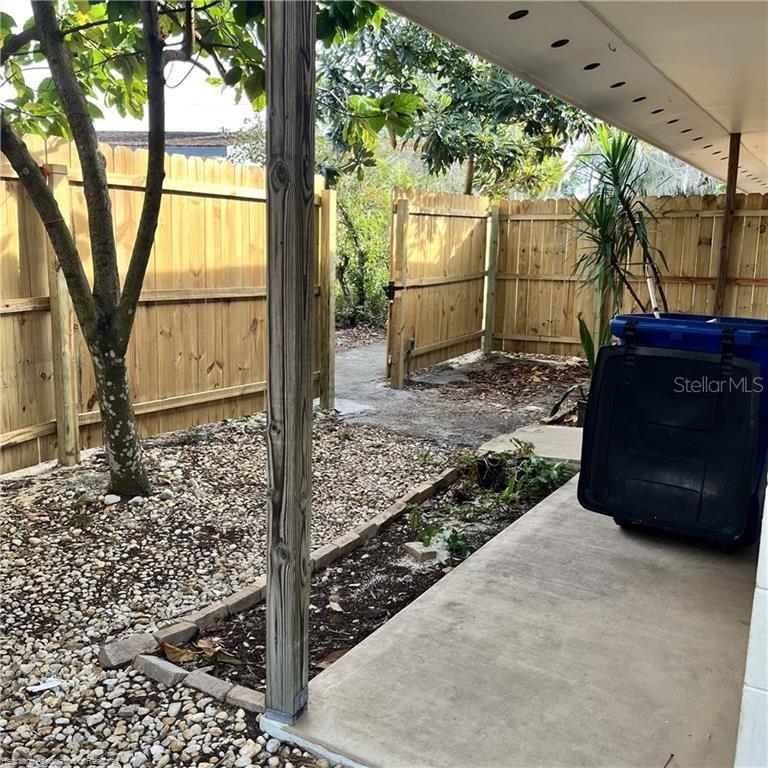 A concrete patio area features a wooden fence, a tree, and a blue trash bin — 231 S ORANGE STREET, SEBRING, FL