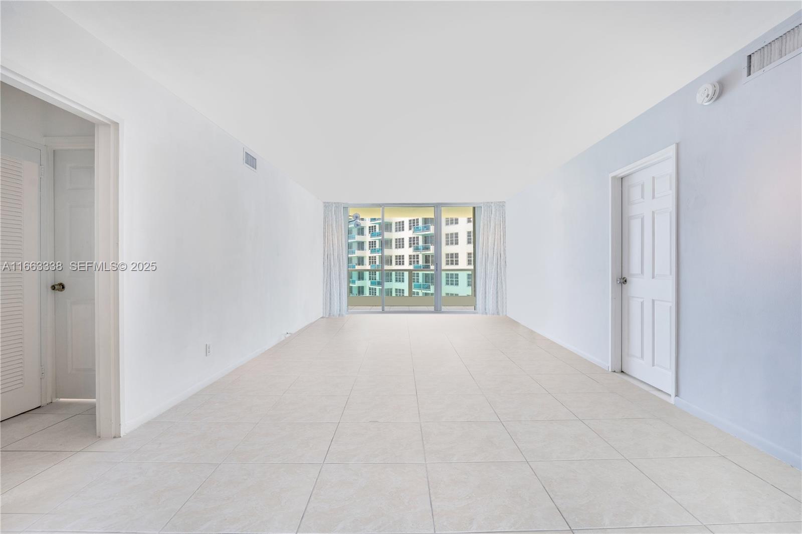 An empty room features white walls, light-colored tile flooring, and a sliding glass door — 5151 Collins Ave # 925, Miami Beach FL 33140, MIAMI BEACH, FL