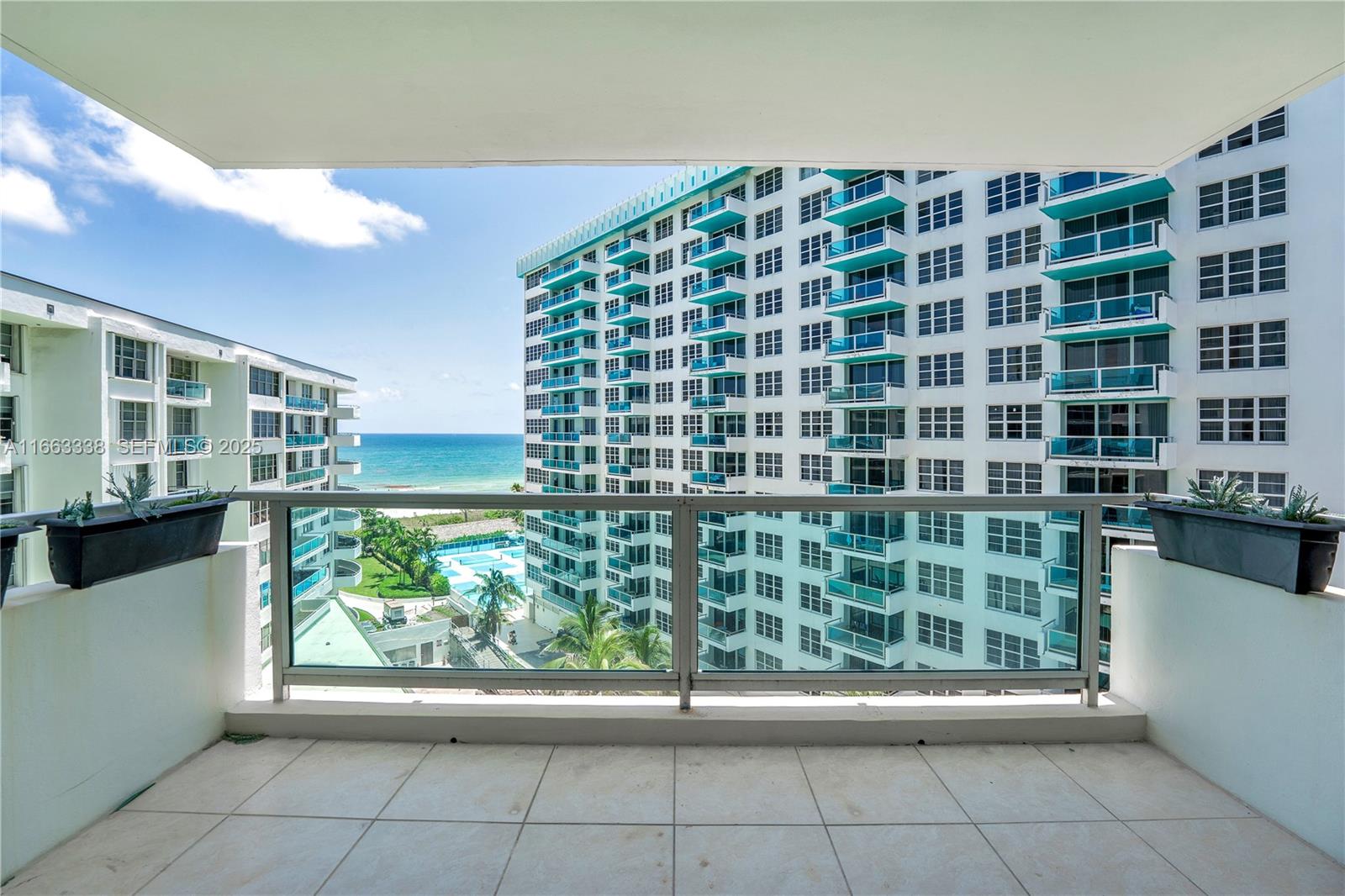 A balcony with tile flooring overlooks a swimming pool, beach, and neighboring high-rise buildings — 5151 Collins Ave # 925, Miami Beach FL 33140, MIAMI BEACH, FL