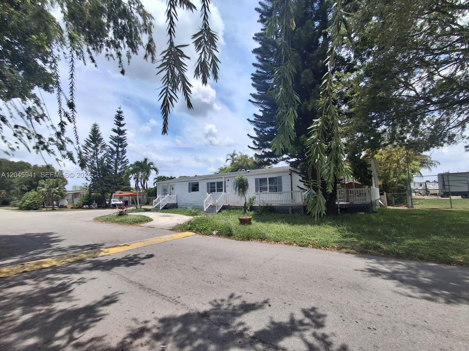 A white manufactured home with a wooden deck sits on a grassy lot — 19800 SW 180 Ave, Miami FL 33187, MIAMI, FL
