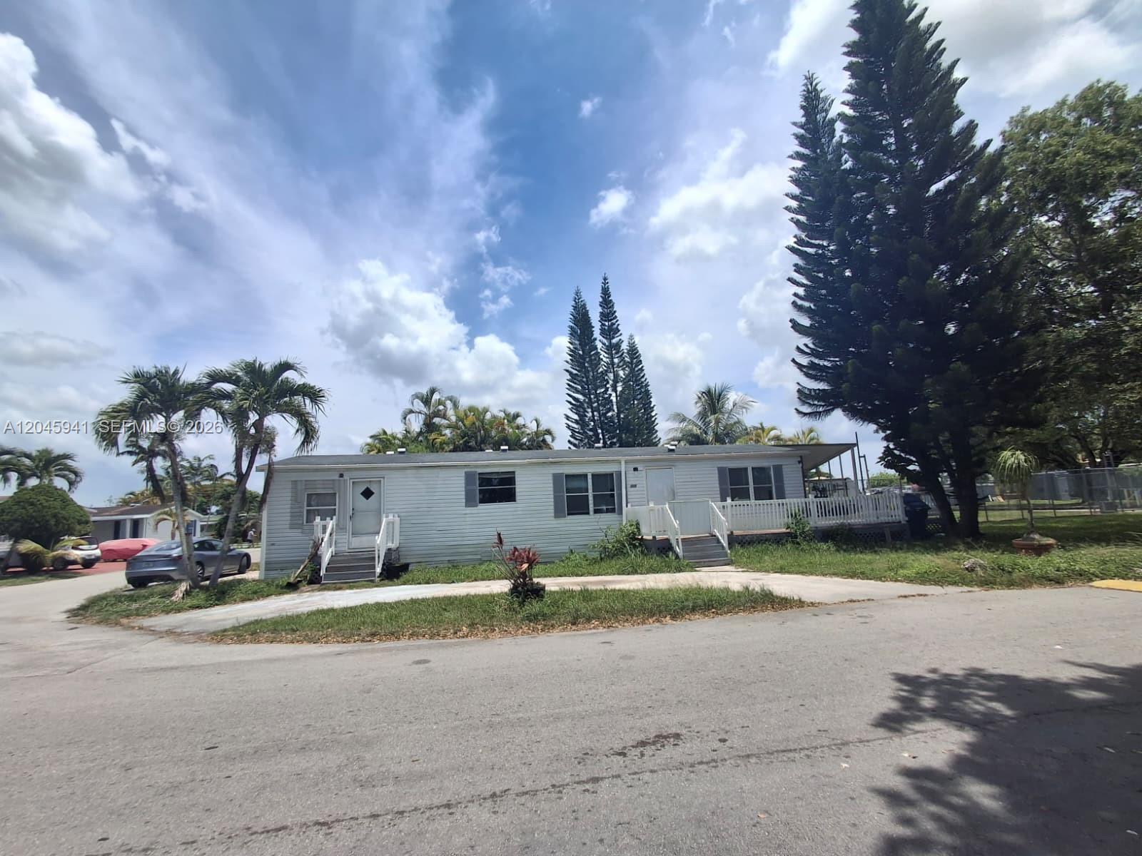 A single-story manufactured home with white siding and a front deck sits on a lot — 19800 SW 180 Ave, Miami FL 33187, MIAMI, FL