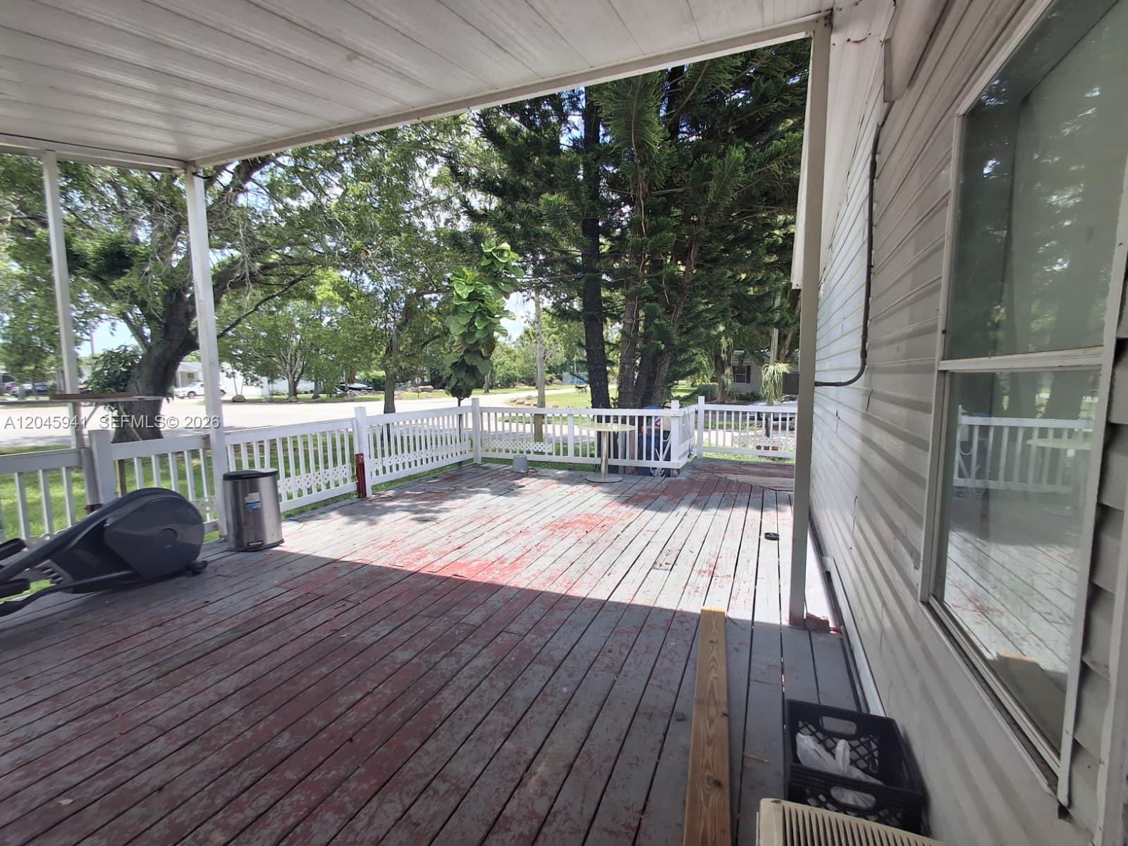 A wooden deck with a white railing is covered by a roof attached to a house — 19800 SW 180 Ave, Miami FL 33187, MIAMI, FL
