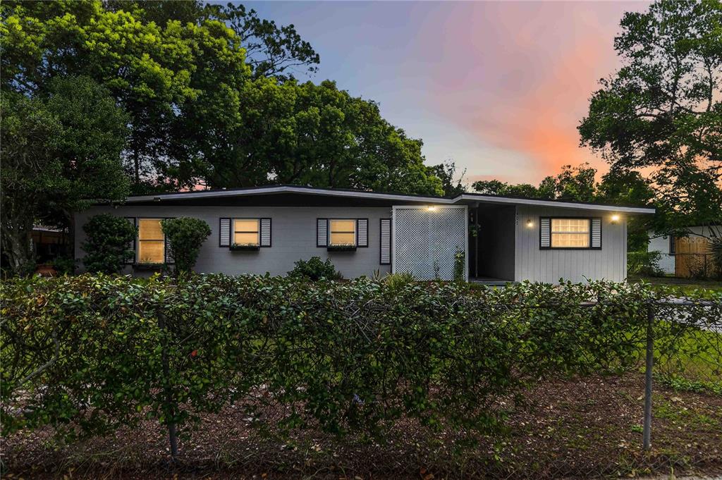 A single-story gray house with a lattice screen and a chain-link fence at dusk — 407 S SUNLAND DRIVE, SANFORD, FL