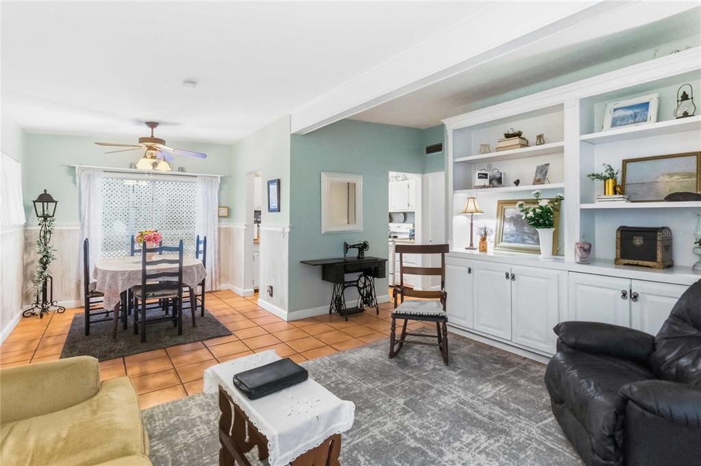 A living room with tile floors, built-in white shelving, a dining area, and a ceiling fan — 407 S SUNLAND DRIVE, SANFORD, FL
