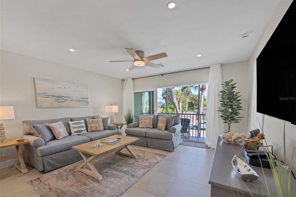 A living room features gray sofas, a wooden coffee table, and a balcony with palm trees — 500 S WASHINGTON DRIVE UNIT 6B, SARASOTA, FL