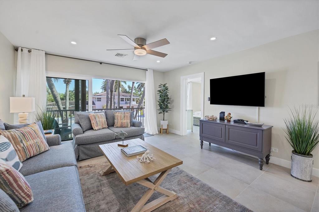 A living room features gray sofas, a wooden coffee table, and a wall-mounted television — 500 S WASHINGTON DRIVE UNIT 6B, SARASOTA, FL
