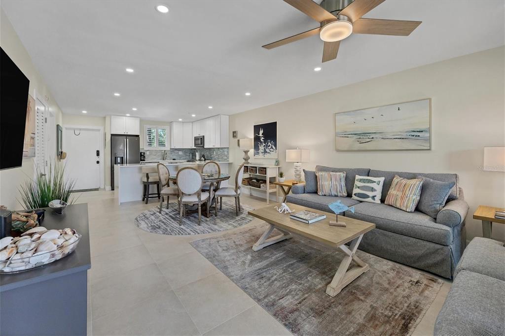 An open-concept living and dining area features a gray sofa, wood coffee table, and kitchen — 500 S WASHINGTON DRIVE UNIT 6B, SARASOTA, FL