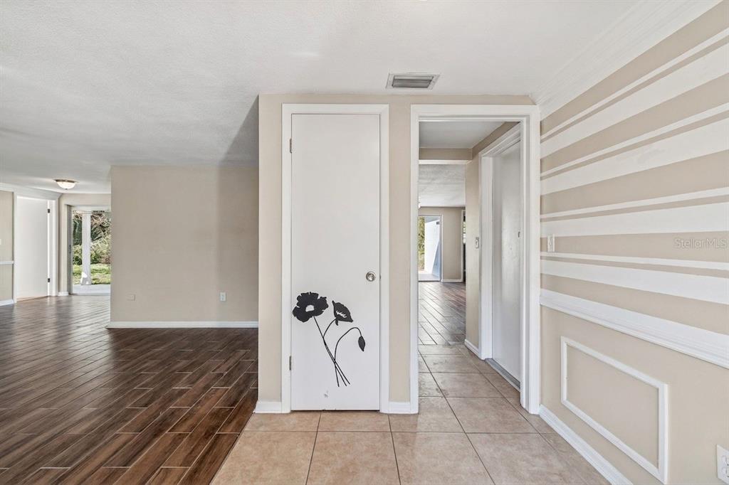 An interior view showing a tiled entryway, a closet with floral decals, and wood flooring — 8210 CLOVER HILL LOOP, HUDSON, FL