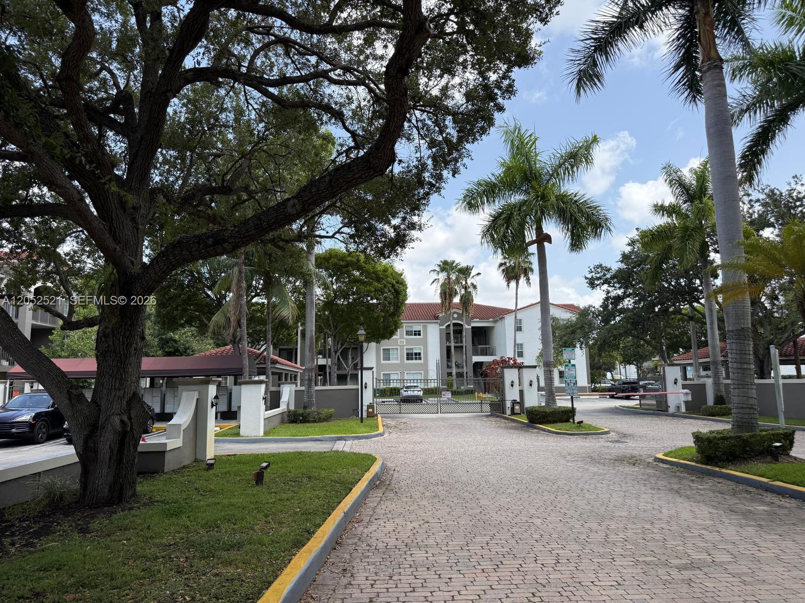A gated entrance with a brick driveway leads to a multi-story apartment building — 6861 SW 44th St # 205, Miami FL 33155, MIAMI, FL