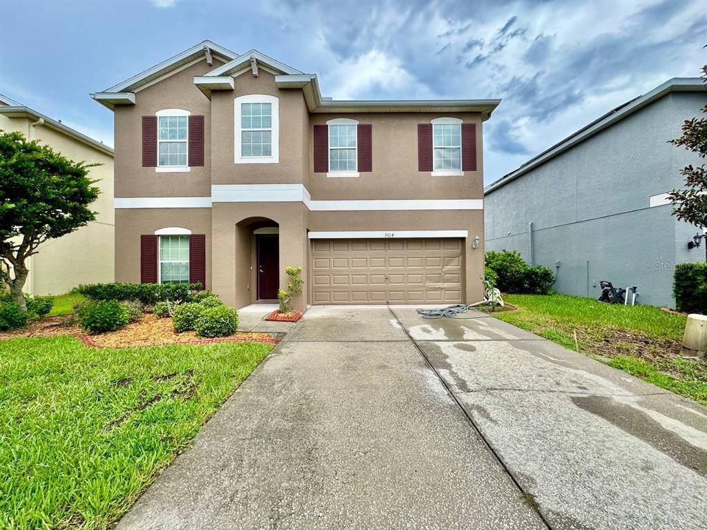 A two-story suburban house with a tan stucco exterior, brown shutters, and a two-car garage — 9614 OAK GLADE AVENUE, TAMPA, FL