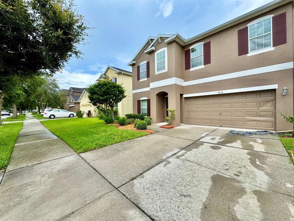 A two-story suburban house with a tan stucco exterior and a two-car garage — 9614 OAK GLADE AVENUE, TAMPA, FL