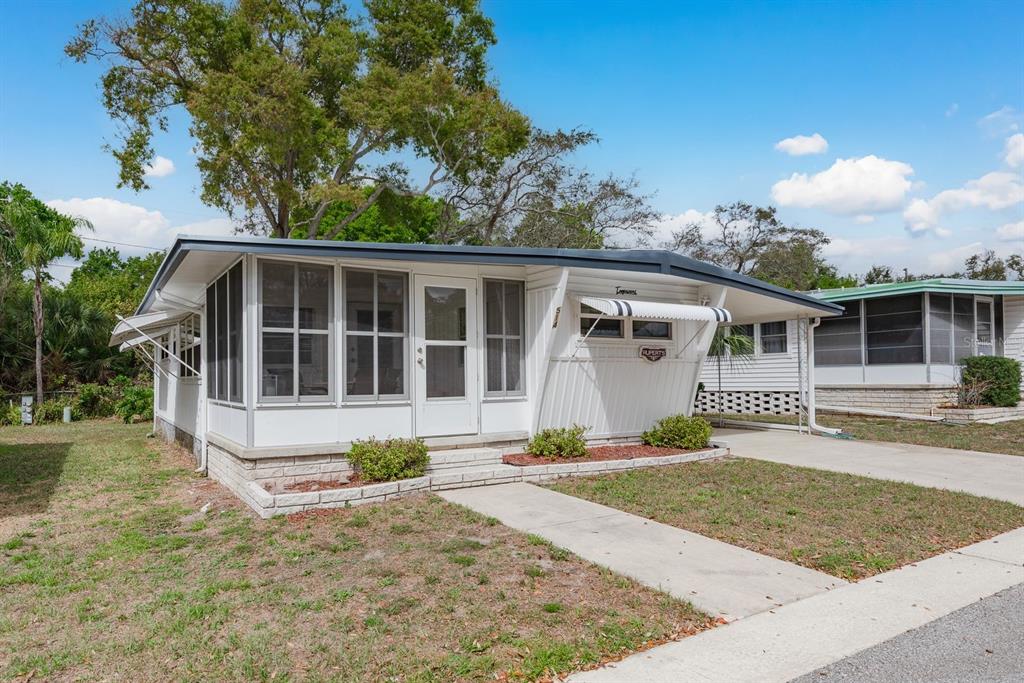 A white mobile home with a screened-in front porch and an attached carport — 2331 BELLEAIR ROAD UNIT 514, CLEARWATER, FL