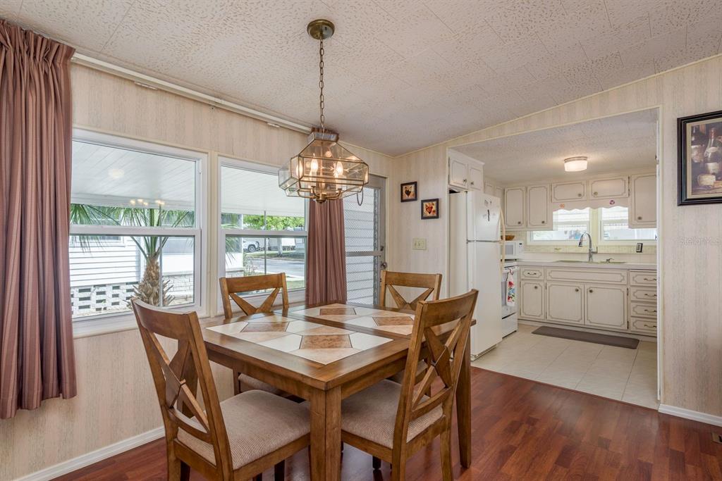 A dining area with a tiled table and wooden chairs opens into a white kitchen — 2331 BELLEAIR ROAD UNIT 514, CLEARWATER, FL