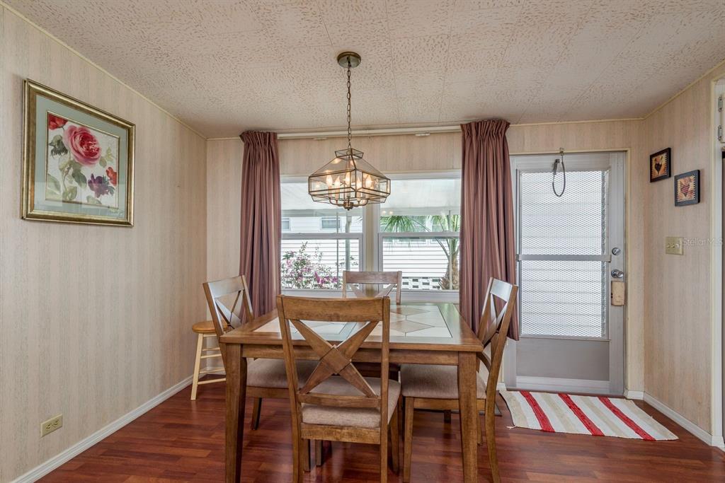 A dining room with a wooden table, chairs, a hanging light fixture, and a screen door — 2331 BELLEAIR ROAD UNIT 514, CLEARWATER, FL