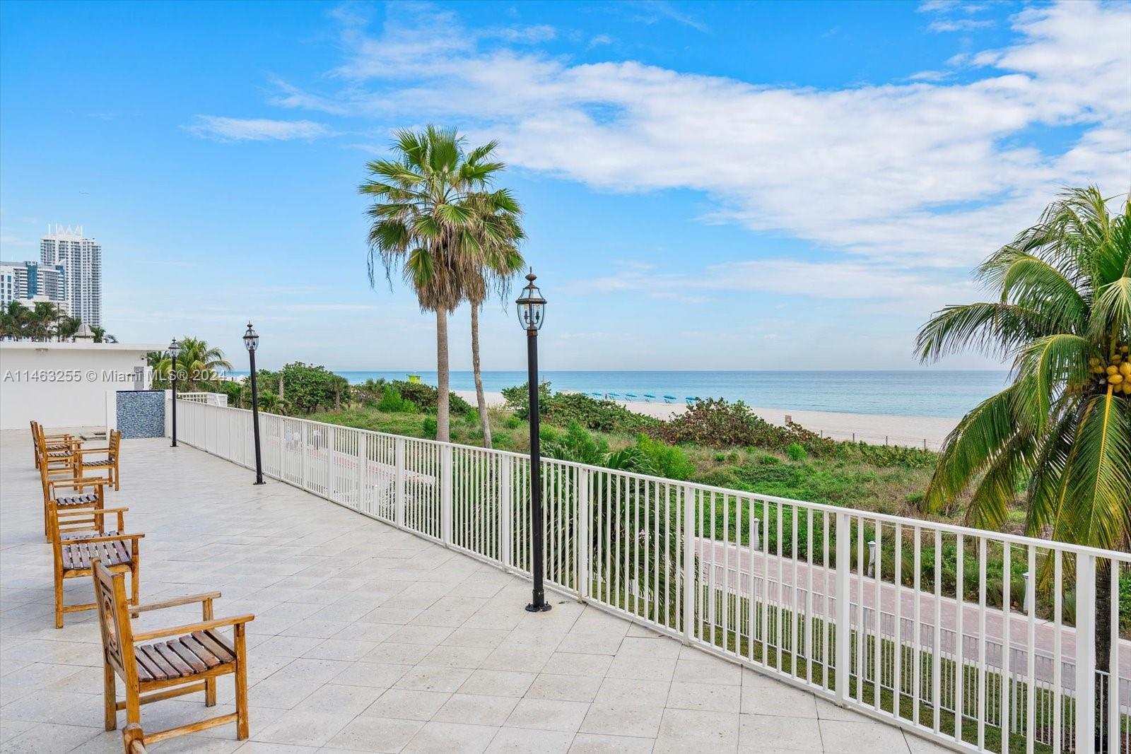 A tiled balcony with wooden chairs overlooks a sandy beach and the ocean — 5601 Collins Ave # 1514, Miami Beach FL 33140, MIAMI BEACH, FL