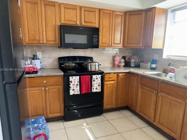 A kitchen features wood cabinets, black appliances, a tiled backsplash, and light-colored floor tiles — 1350 NE 119th St # 25, Miami FL 33161, MIAMI, FL