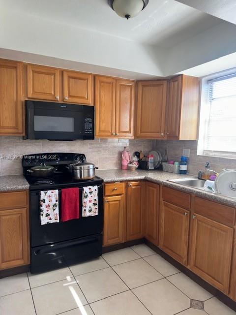 A kitchen features wood cabinets, a black microwave, a black stove, and tiled flooring — 1350 NE 119th St # 25, Miami FL 33161, MIAMI, FL