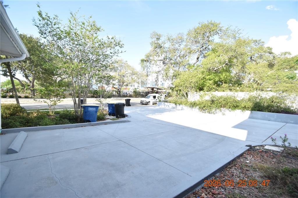 A concrete driveway and parking area sit in front of trees and a white fence — 1254 GROVE STREET UNIT B, CLEARWATER, FL