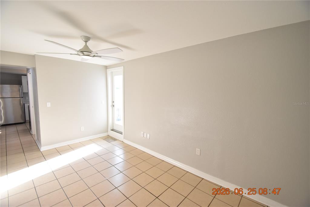 An empty room with beige tile flooring, light gray walls, a ceiling fan, and a door — 1254 GROVE STREET UNIT B, CLEARWATER, FL