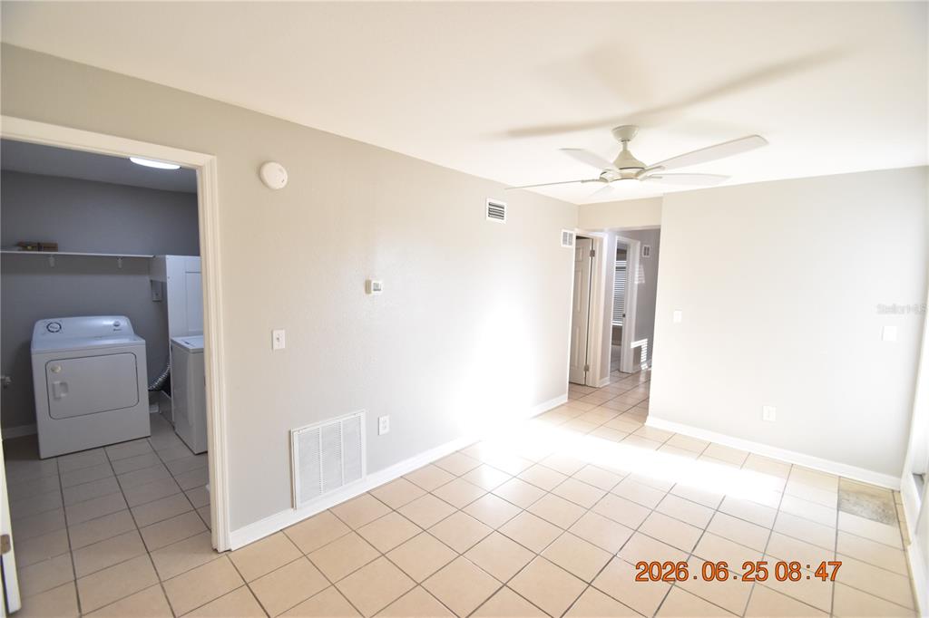 A room with light-colored tile flooring, a ceiling fan, and an adjacent laundry area — 1254 GROVE STREET UNIT B, CLEARWATER, FL