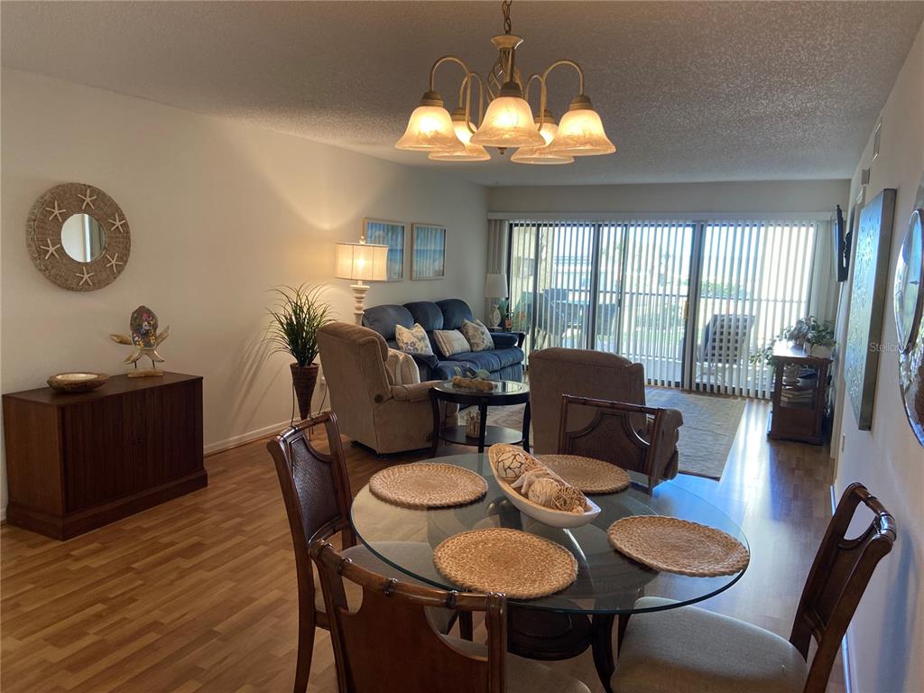 A dining area with a glass table opens into a living room with sliding doors — 700 GOLDEN BEACH BOULEVARD UNIT 131, VENICE, FL