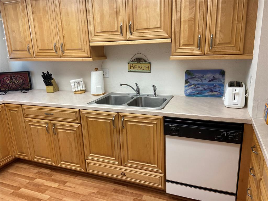 A kitchen features light wood cabinets, a double-basin stainless steel sink, and a white dishwasher — 700 GOLDEN BEACH BOULEVARD UNIT 131, VENICE, FL