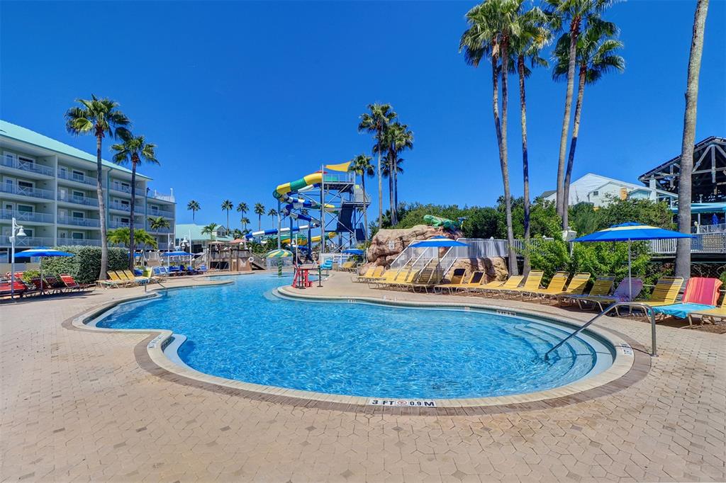 A swimming pool with a water slide and lounge chairs sits outside a resort building — 399 2ND STREET UNIT 716, INDIAN ROCKS BEACH, FL