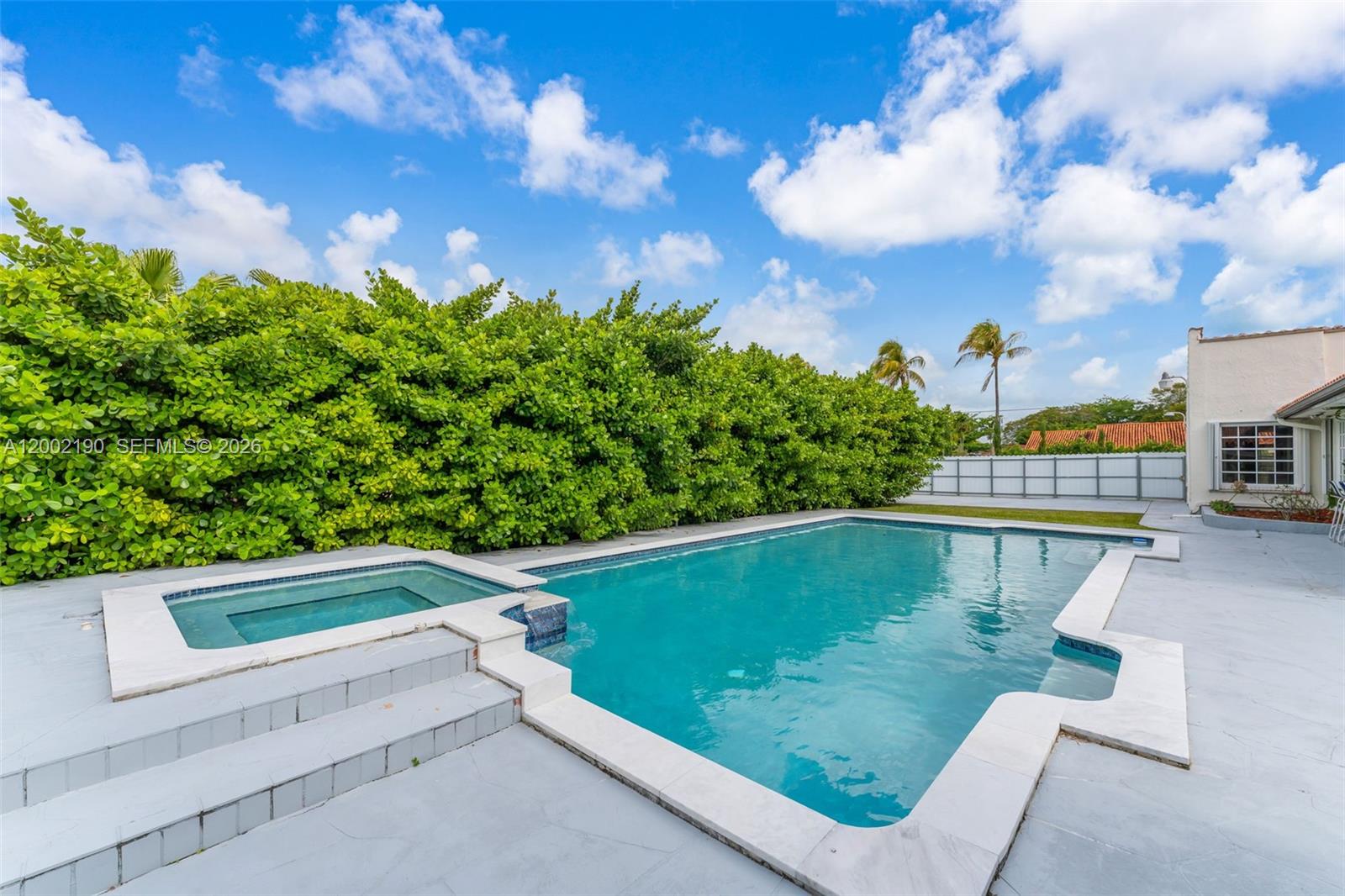 A swimming pool with an attached spa sits on a patio beside a large hedge — 11350 SW 30th St, Miami FL 33165, MIAMI, FL