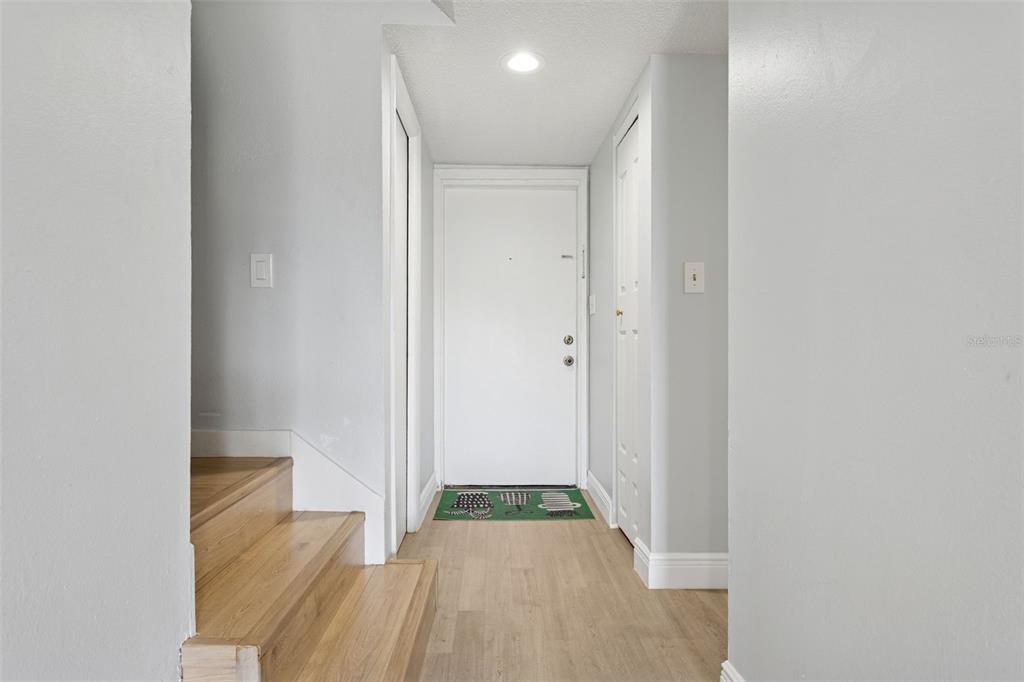 An entryway features light wood flooring, a white front door, and stairs on the left — 5110 TENNIS COURT CIRCLE UNIT 86, TAMPA, FL