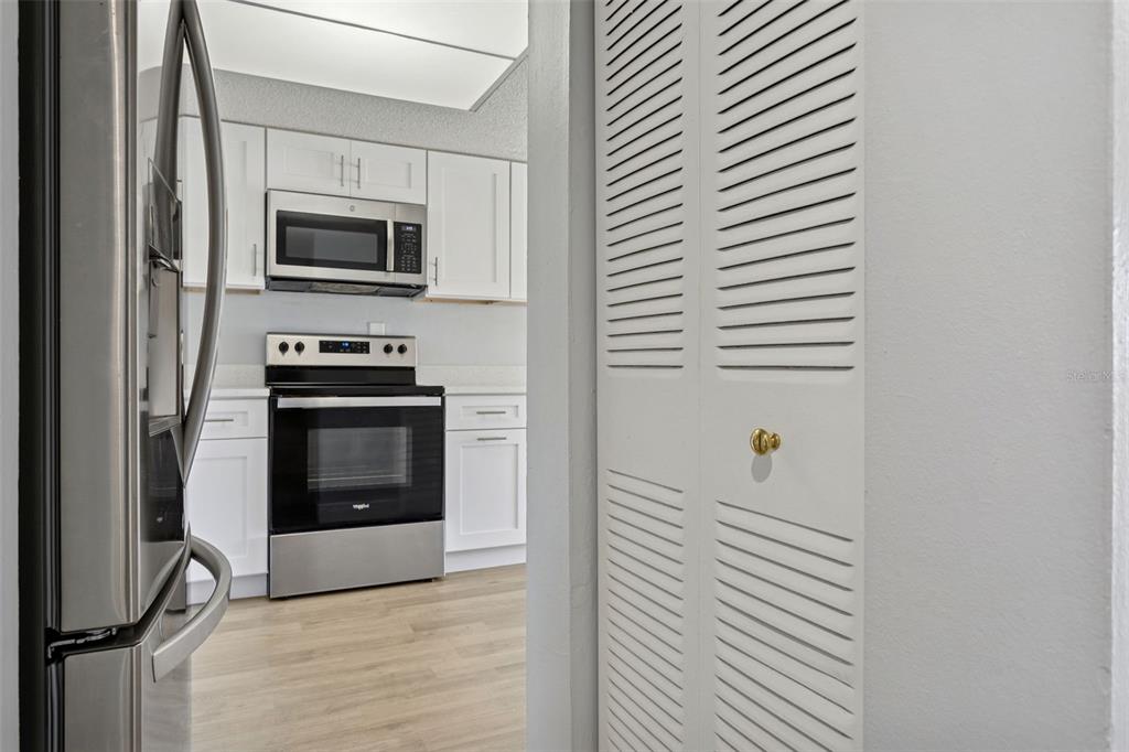 A view through a doorway into a kitchen with white cabinets and stainless steel appliances — 5110 TENNIS COURT CIRCLE UNIT 86, TAMPA, FL