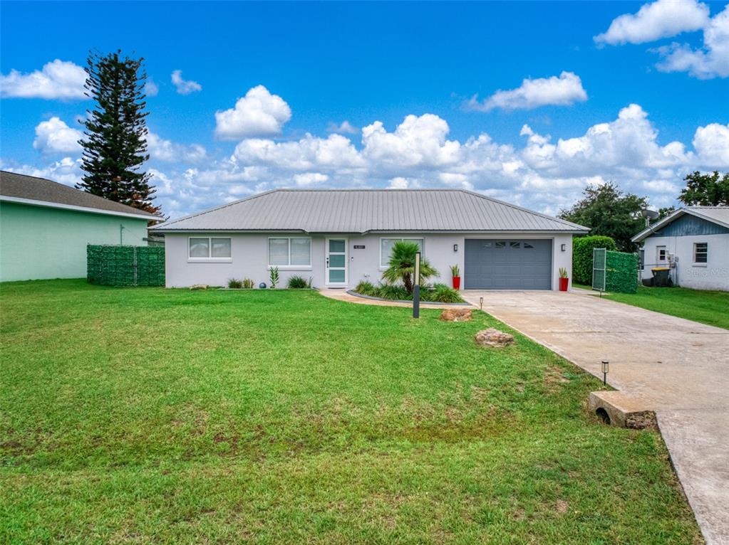 A single-story house with a gray metal roof, gray garage door, and a concrete driveway — 4224 LAKE VISTA DRIVE, SEBRING, FL