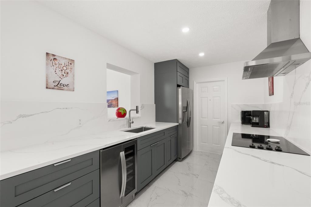 A modern kitchen features dark gray cabinetry, white marble-style countertops, and stainless steel appliances — 4224 LAKE VISTA DRIVE, SEBRING, FL