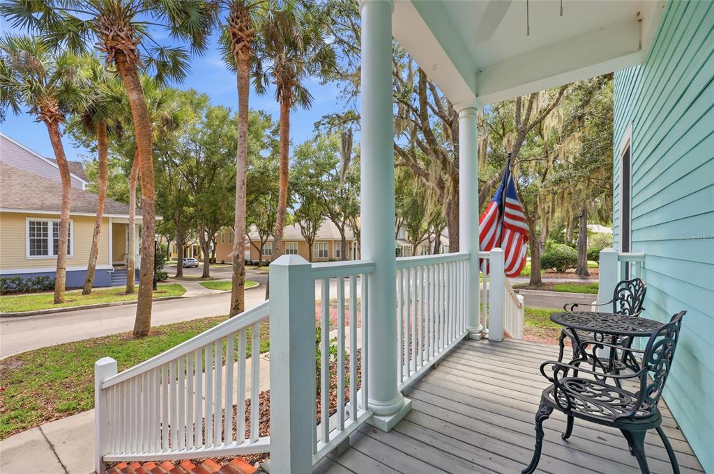 A covered porch with white railings, a small bistro set, and an American flag — 4855 SW 91ST WAY, GAINESVILLE, FL