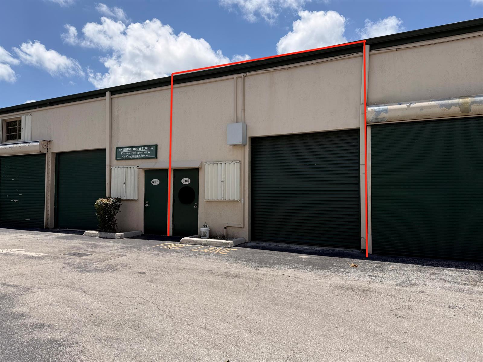 An exterior view of a commercial building featuring two green roll-up doors and two entrances — 1791 Blount Road # 606, Pompano Beach FL 33069, POMPANO BEACH, FL