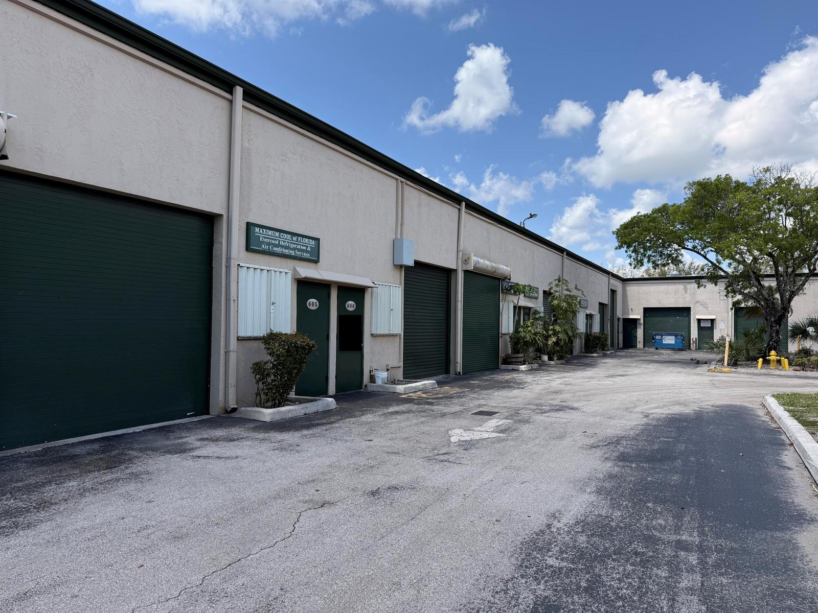 An exterior view of a commercial warehouse building with multiple roll-up doors and entrances — 1791 Blount Road # 606, Pompano Beach FL 33069, POMPANO BEACH, FL