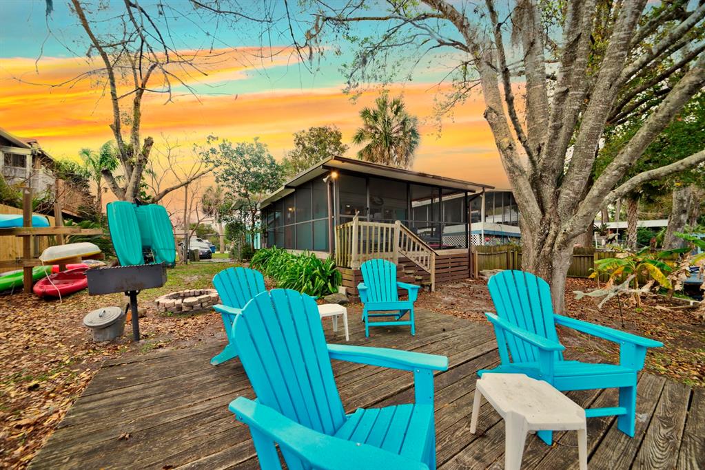 A wooden deck features three bright blue Adirondack chairs and a small table outdoors — 6427 W RICHARD DRIVE, WEEKI WACHEE, FL