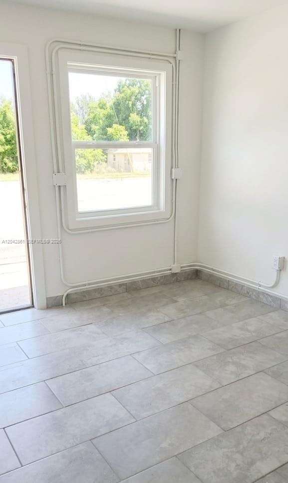 A room with light gray tile flooring, white walls, and exposed electrical conduit — 240 SW 6th St # 1, Belle Glade FL 33430, BELLE GLADE, FL
