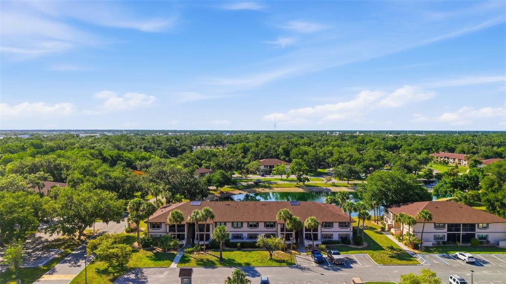 A multi-story apartment building sits behind a pond with a fountain in the foreground — 19505 QUESADA AVENUE UNIT AA204, PORT CHARLOTTE, FL