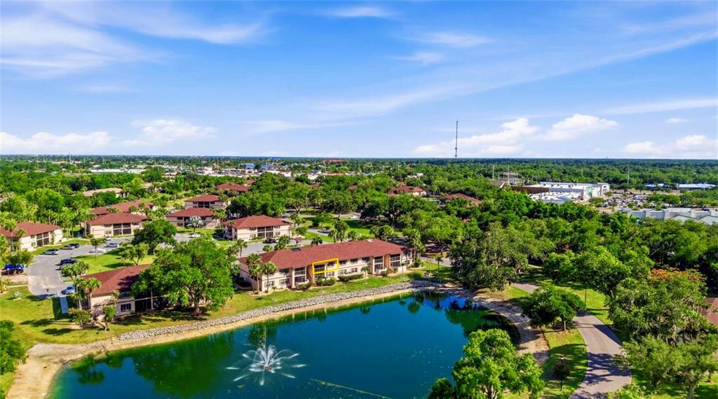 An aerial view shows a multi-story apartment building with a parking lot and a pond — 19505 QUESADA AVENUE UNIT AA204, PORT CHARLOTTE, FL