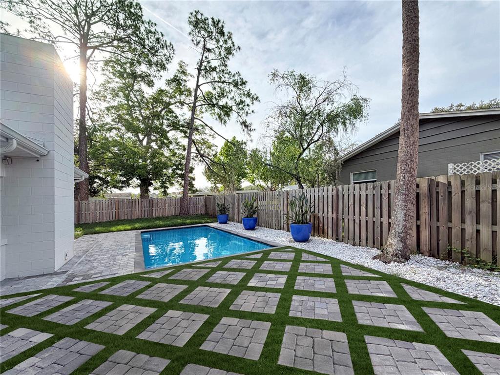 A backyard features a rectangular swimming pool, paver patio, artificial turf, and a wooden fence — 20 E DIVISION STREET, WINTER GARDEN, FL